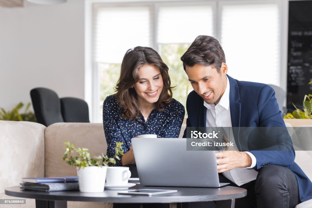 Modern business people working at a cafe Two business colleagues sitting in a cafe and working on laptop. Business couple having a meeting in cafe. Laptop Stock Photo