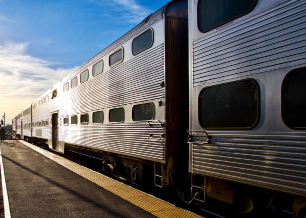 treno che lascia la stazione e scompare al tramonto all'ora di punta - treno pendolare foto e immagini stock