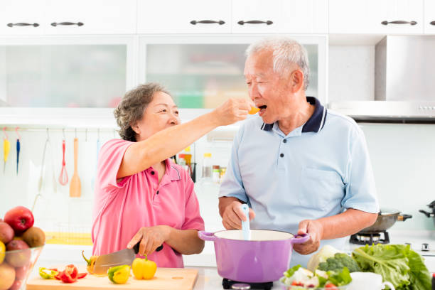 feliz pareja senior de cocción en cocina - healthy feeding fotografías e imágenes de stock