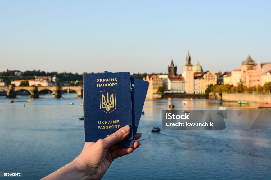 Woman's hand holding two Ukrainian passports in front of Prague old town cityscape Woman's hand holding two Ukrainian passports in front of Prague old town cityscape. Travel concept Architecture Stock Photo