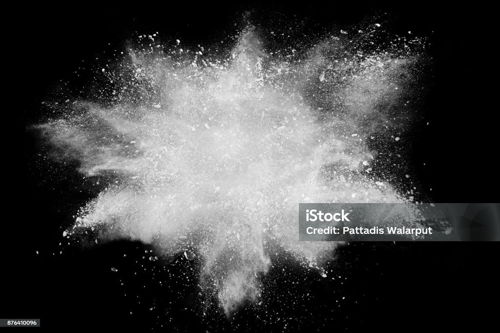 Freeze motion explosion of white dust on  black background. By throwing talcum powder out of hand. Stopping the movement of white powder on dark background. Flour Stock Photo