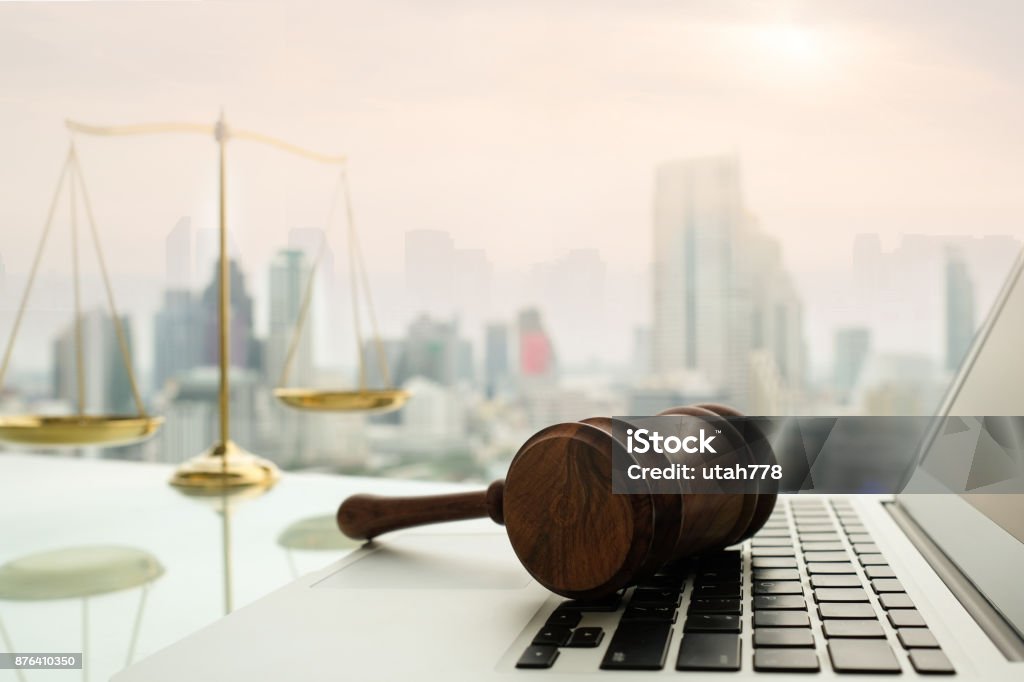 law legal technology law legal technology concept. Wooden gavel on laptop keyboard with scales of justice in business city background. Law Stock Photo