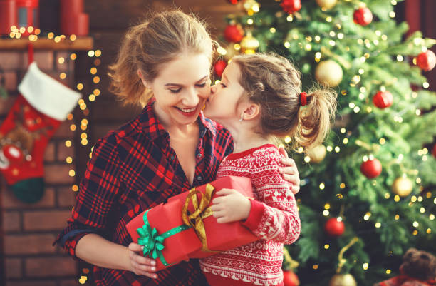 felice famiglia madre e figlia dando regalo di natale - christmas family child christmas tree foto e immagini stock