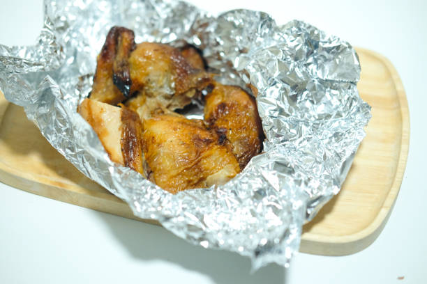 istock Roasting chicken in foil on wooden tray 876420610