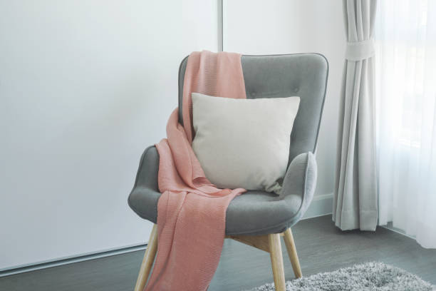 Pink scarf and beige pillow on gray armchair at the corner of living room stock photo