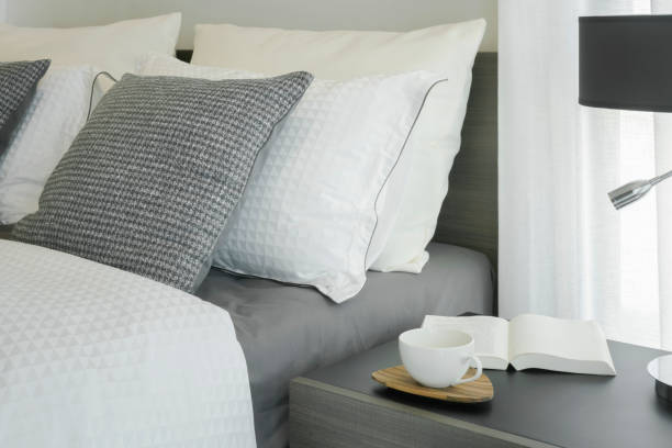 istock White coffee cup and book on wooden night table next to bed 876427384
