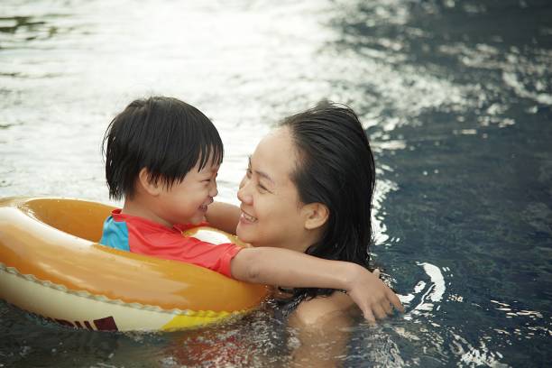 istock Young Mother and her son having fun together playing at swimming pool 876431000