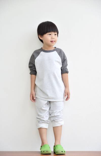 Happy child little boy standing at white wall background stock photo