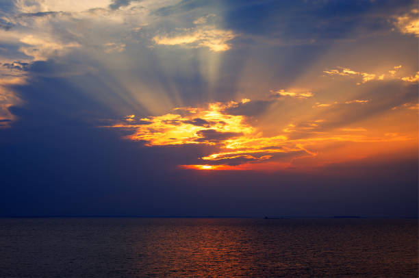 istock Sunset rays through a cloudy dark sky over the lake 876431330
