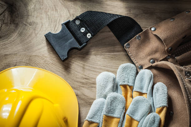 istock Leather construction belt safety gloves hard hat on wooden board 876450228