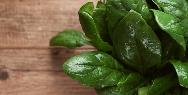 istock wet spinach leaves on a wooden background 876463200