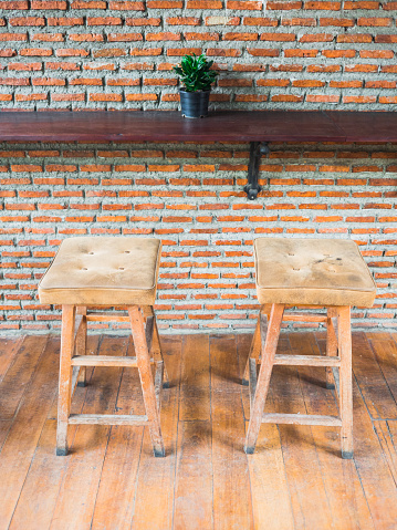 The empty cafe (Coffee shop), wooden chairs with leather seat near the bar against red/orange brick wall