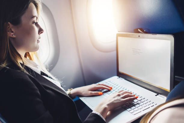 istock Young female student learning online via netbook while sitting in an airplane cabin 876474122