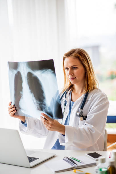 врач-женщина с рентгеном, работающая за офисным столом. - human lung audio стоковые фото и изображения