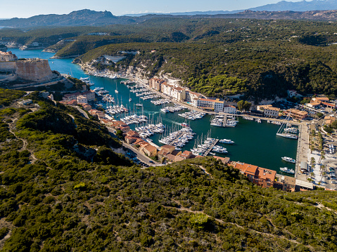 Aerial view of Bonifacio old town built on cliffs of white limestone, cliffs. Harbor. Corsica, France. Strait of Bonifacio separating Corsica from Sardinia