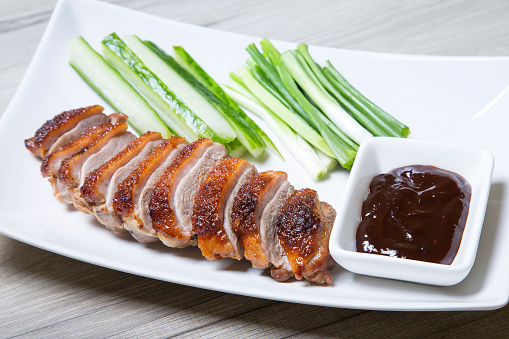 Baked duck with hoisin sauce, cucumbers and shallots. Selective focus, close-up.