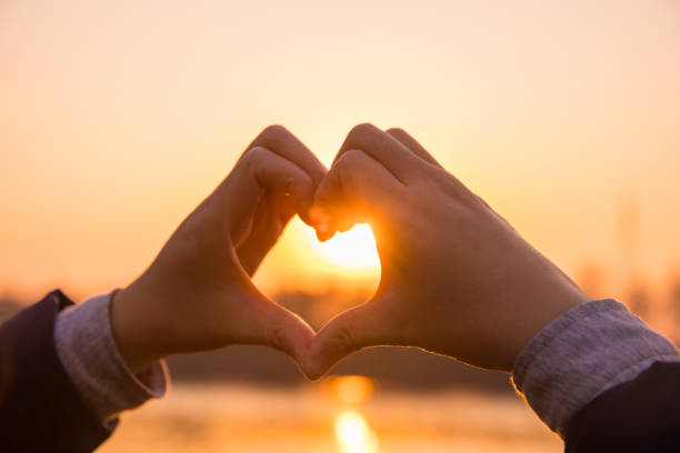 istock Woman making a hand shaped heart at sunset 876487398