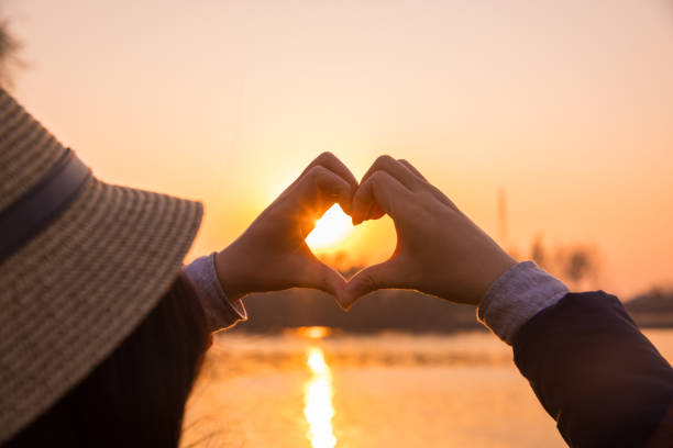 istock Woman making a hand shaped heart at sunset 876487574