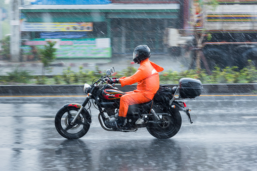 Nonthaburi: Motion Blurred panning photo of Unidentified name people riding motorcycle in the rain on road at Nonthaburi, Thailand.