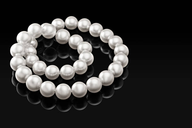 istock Luxury white pearl necklace on a black background with glossy reflection 876504086