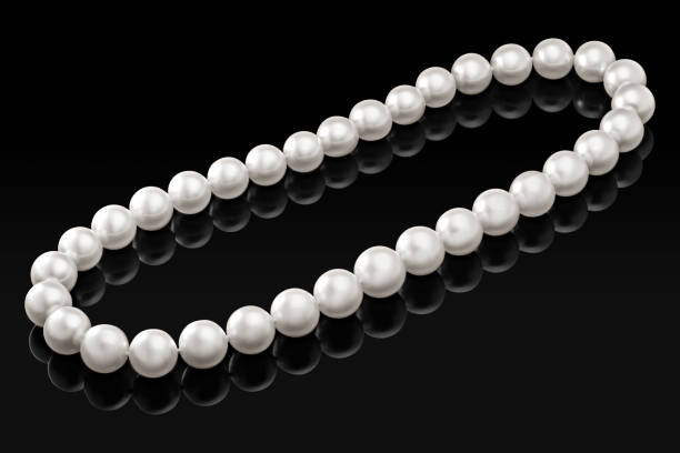 istock Luxury white pearl necklace on a black background with glossy reflection 876504104
