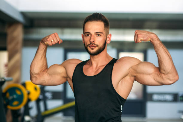 istock Young athlete posing with a torso for photography on a brick wall background. Bodybuilder, athlete with pumped muscles, breast and arm rescue 876509000