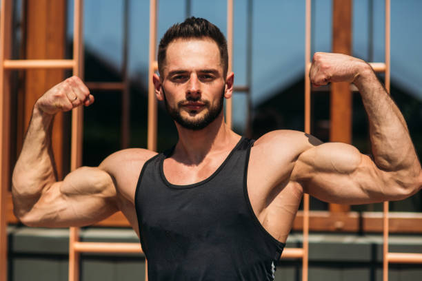 istock Young athlete posing with a torso for photography on a brick wall background. Bodybuilder, athlete with pumped muscles, breast and arm rescue. 876511784