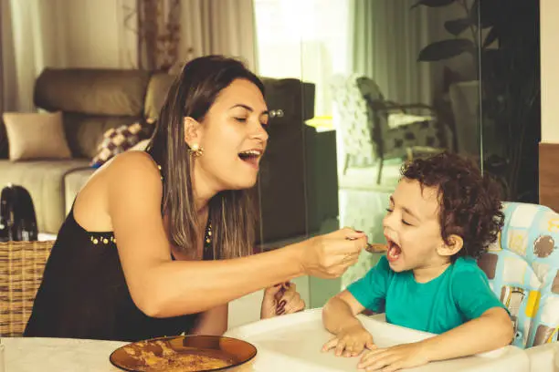 Mother feeding her son in the dining table.