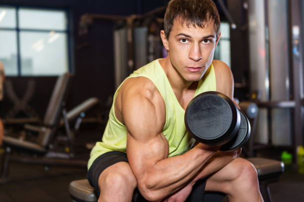 istock Young man exercising with weight in the gym 876523726
