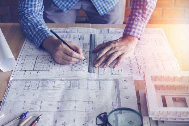istock Concept architects,engineer holding pen pointing equipment architects On the desk with a blueprint in the office, Vintage, Sunset light.Selective Focus 876524274
