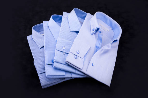istock A set of 4 men's shirts in blue tones, folded on a black background. 876526532