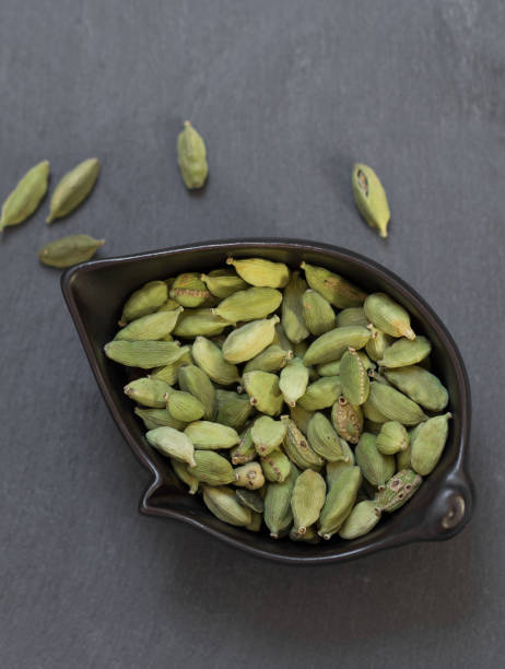 cardamom in bowl on grey stone background cardamom in bowl closeup on grey slate background top view cardamom stock pictures, royalty-free photos & images