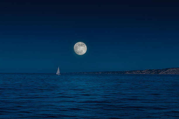 full moon over horizon of sea at night