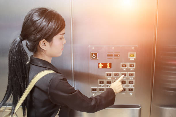 istock businesswomen pressing elevator button with sun light effect. businesswomen is in elevator. 876545118