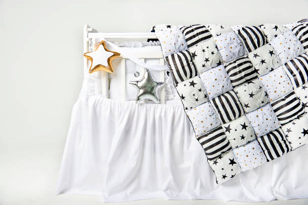 istock Silver and gold star shaped pillows and patchwork comforter on a white baby cot 876550814