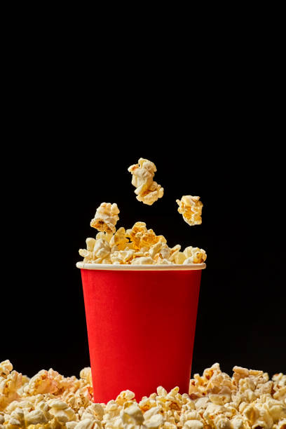 istock Popcorn falling into red bucked isolated on black background with copy space 876554330
