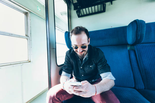 istock Hipster man traveling with train and using smart phone 876558128