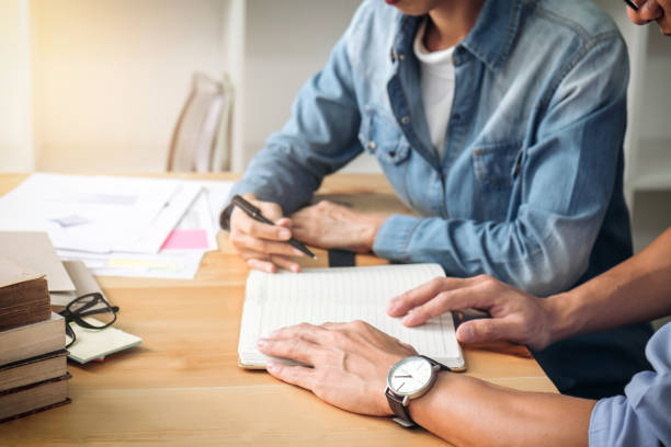 istock Tutor books with friends, Young students campus or classmates helps friend catching up workbook and learning tutoring in classroom, teaching, learning, People, technology, Education school concept 876563844