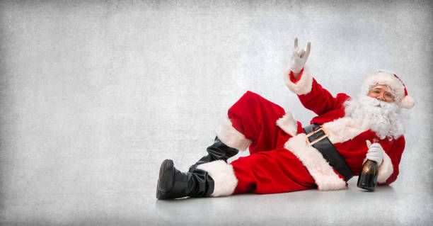 Happy Santa Claus lying on the floor with a bottle of wine Drunk and happy Santa Claus lying on the floor with a bottle of wine and makes a hand sign christmas human hand christmas ornament decoration stock pictures, royalty-free photos & images