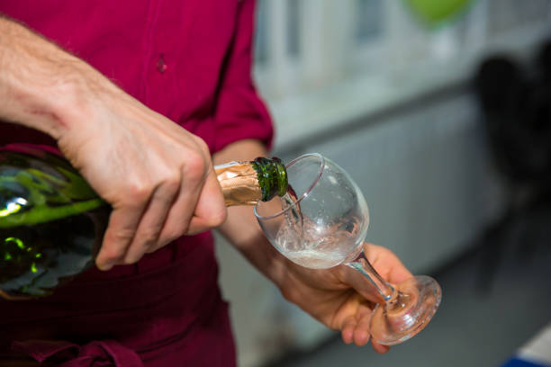 Close-up of waiter pouring champagne into champagne flutes at party
