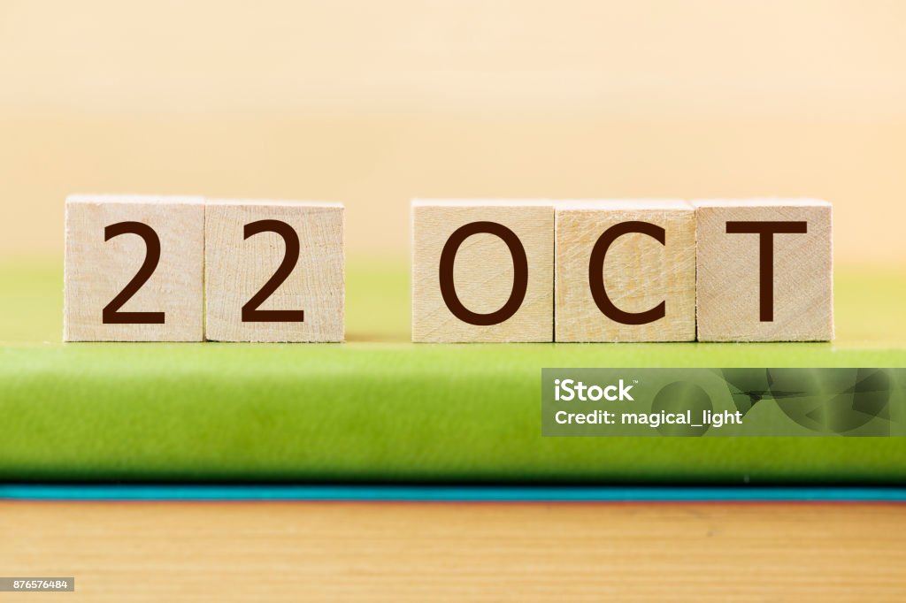 Wooden cube shape calendar for OCT 22 on green book, table. 2018 Stock Photo