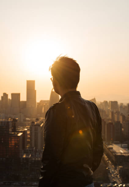 vue arrière de l’homme en regardant la ville du soleil - rear view men business back photos et images de collection