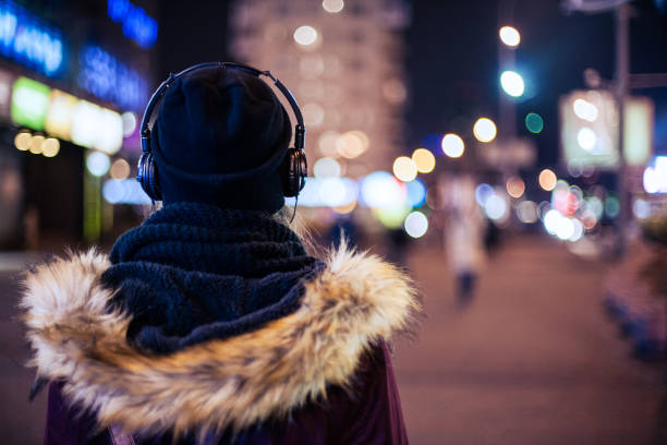 chica caminando por la calle escuchando la música de la ciudad de noche - city street audio fotografías e imágenes de stock