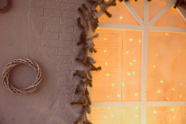 Spruce branches with illuminated garlands window. Spruce branches with illuminated garlands window. Background woven wreath of smooth branches against a brick wall background pine log state forest stock pictures, royalty-free photos & images