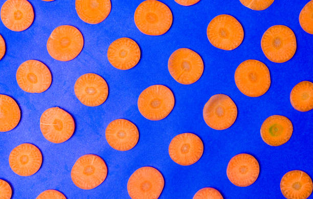 istock Carrot slices on blue background flat lay 876593282
