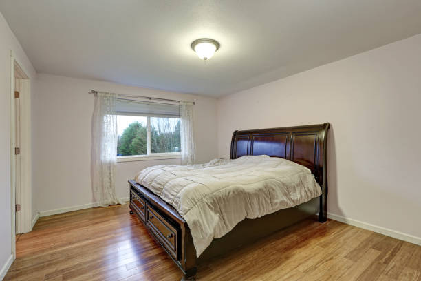 istock White bedroom with dark stained wood bed with lower drawers 876593812
