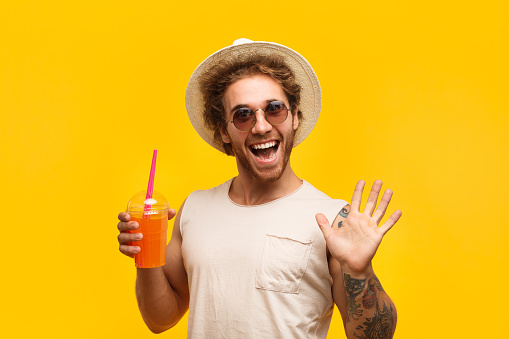 Funny man wearing hat and holding cup of drink.