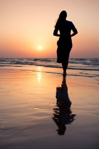 istock Girl on the beach at sunset 876597010