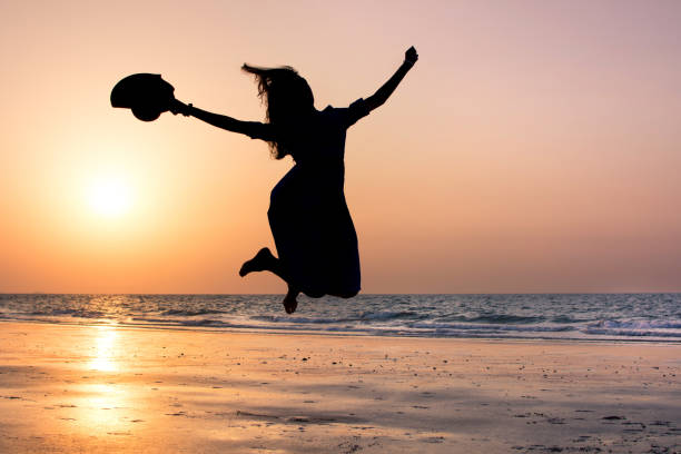 istock Happy girl jumping on the beach at sunset 876597610