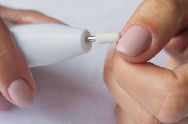 istock Manicure. Female hands with electric nail trimmer. 876601152